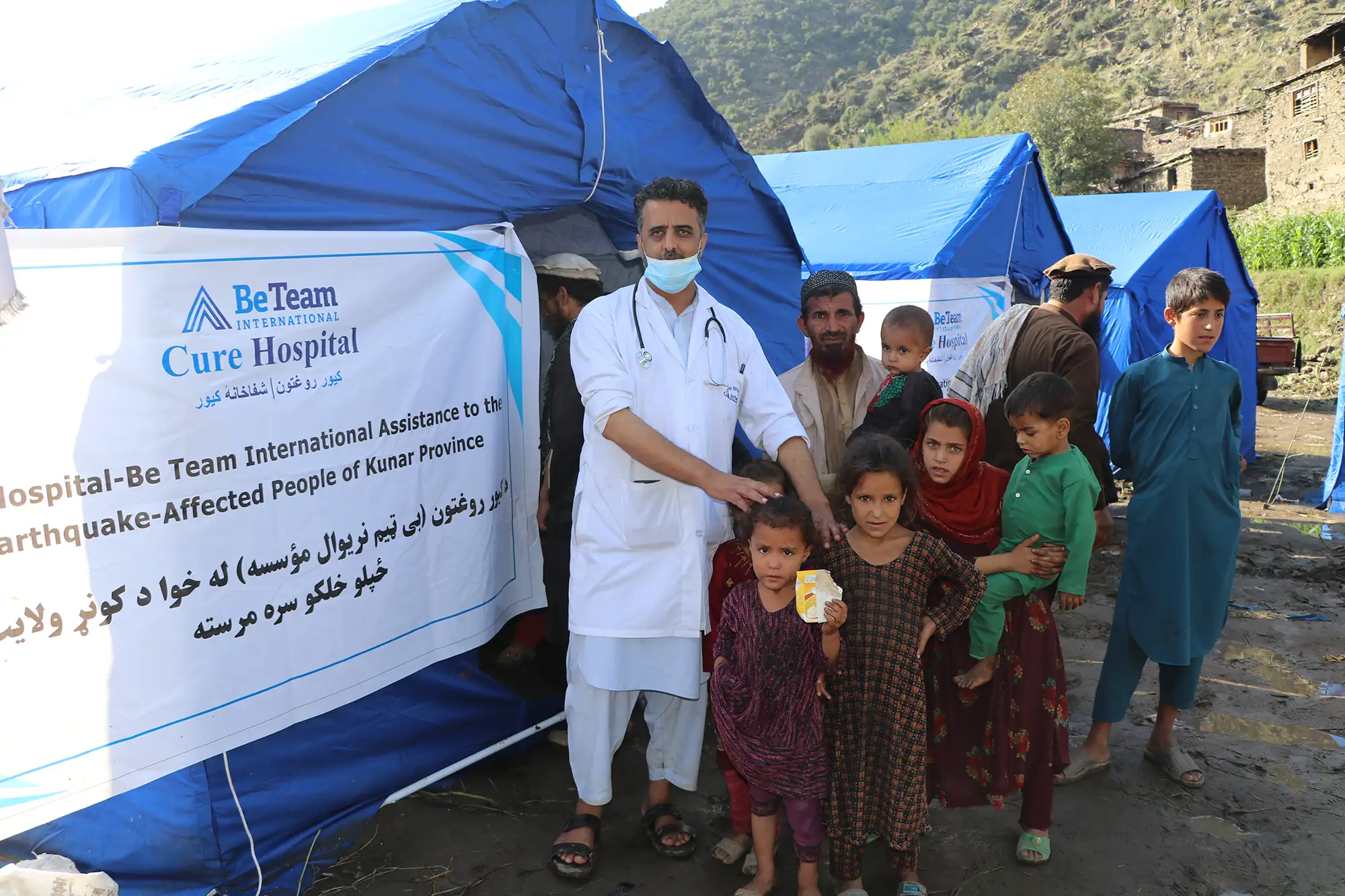 Be Team International Cure Hospital doctor caring for a father and children during a crisis response medical camp in remote Afghanistan