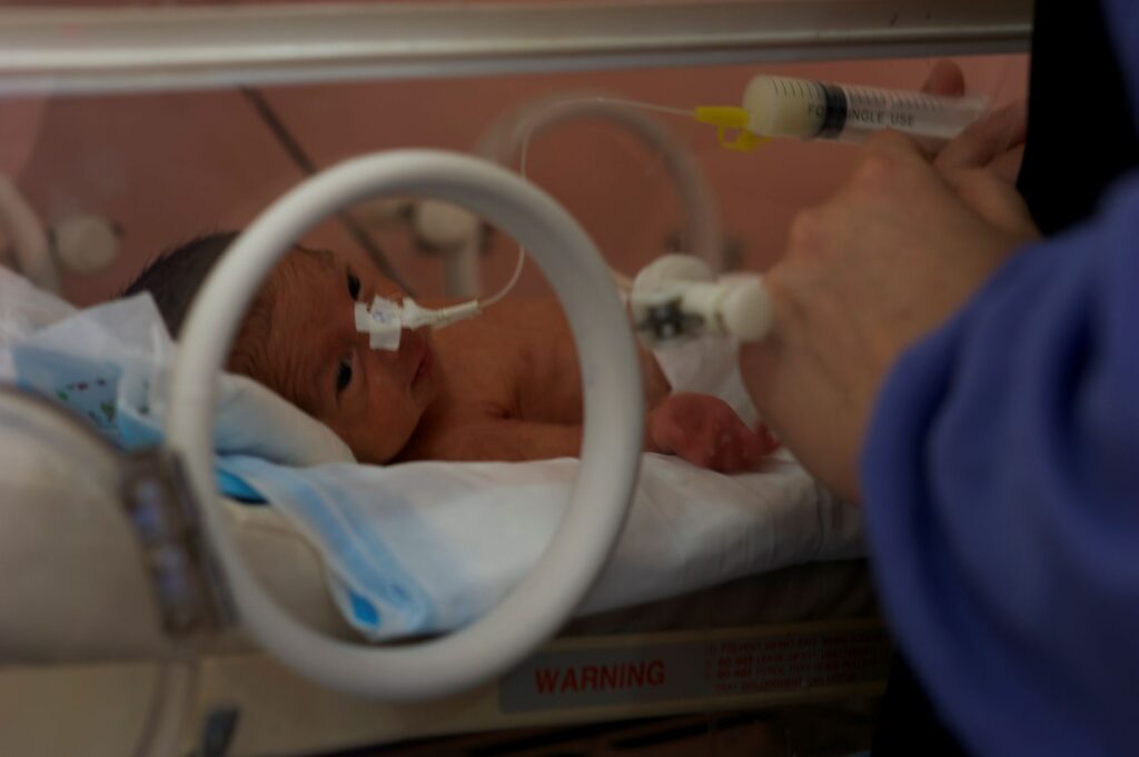 Nurse reaching into NICU crib to care for a newborn baby at Be Team International's Cure Hospital in Kabul, Afghanistan
