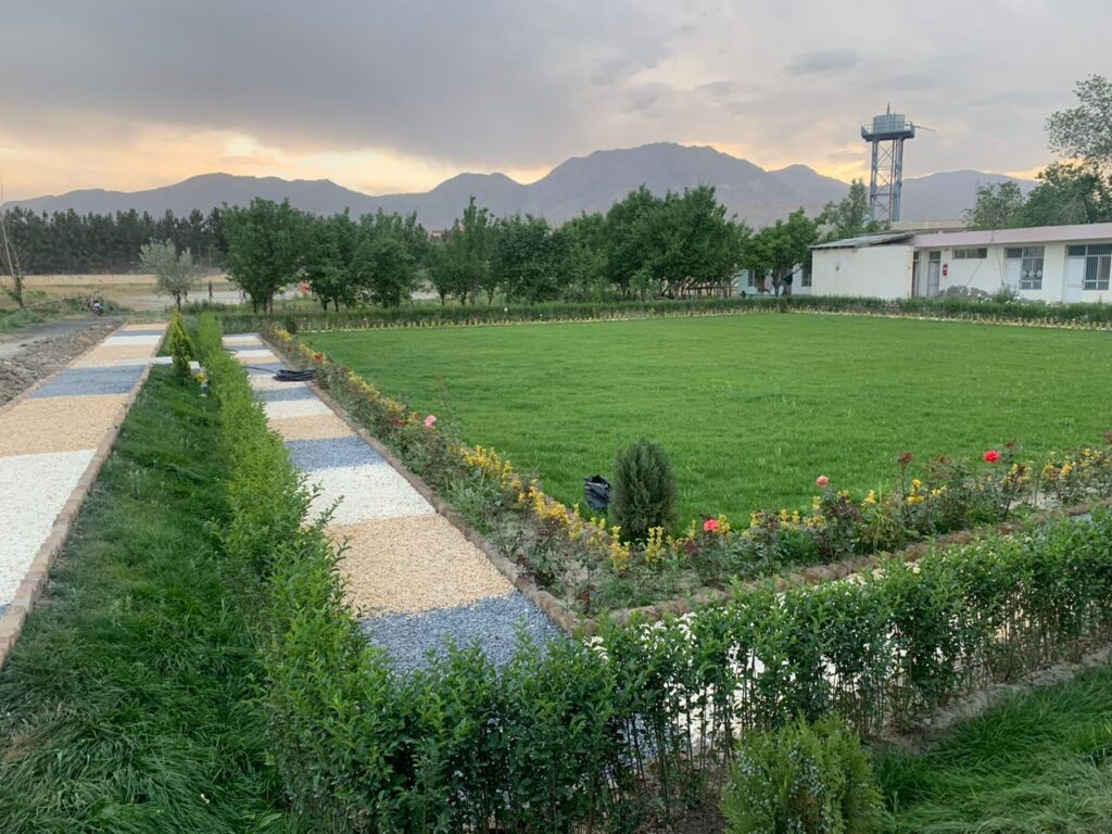 Sunset over Be Team International's Cure Hospital grounds in Kabul, Afghanistan, with a colorful decorative garden border in the foreground