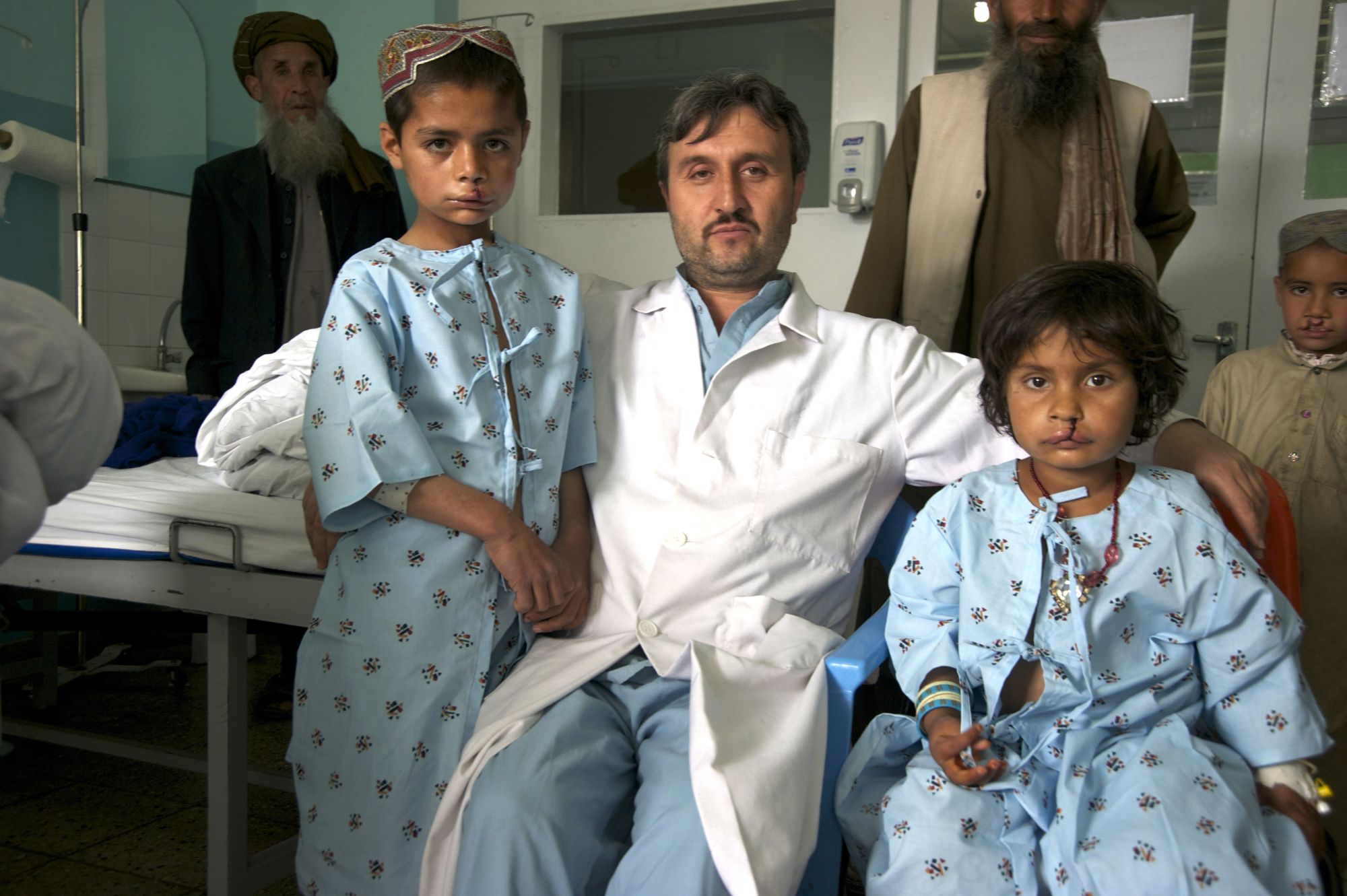 Surgeon seated with two young children recovering from cleft lip palate surgery at Be Team International's Cure Hospital in Kabul, Afghanistan