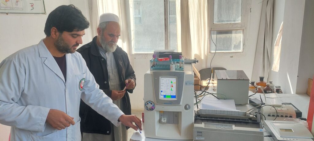 Lab technician and colleague working with laboratory equipment at Be Team International's Cure Hospital in Kabul, Afghanistan