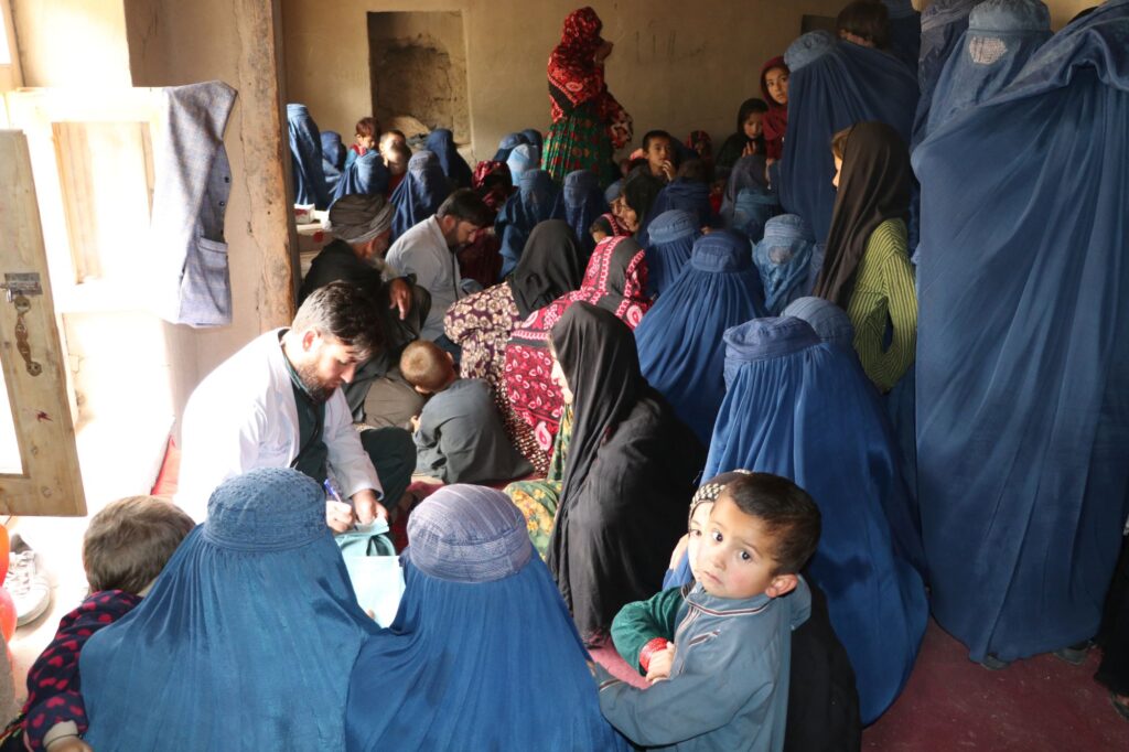 Be Team International Cure Hospital doctor surrounded by women and children seeking care at a medical camp in Baghlan, Afghanistan