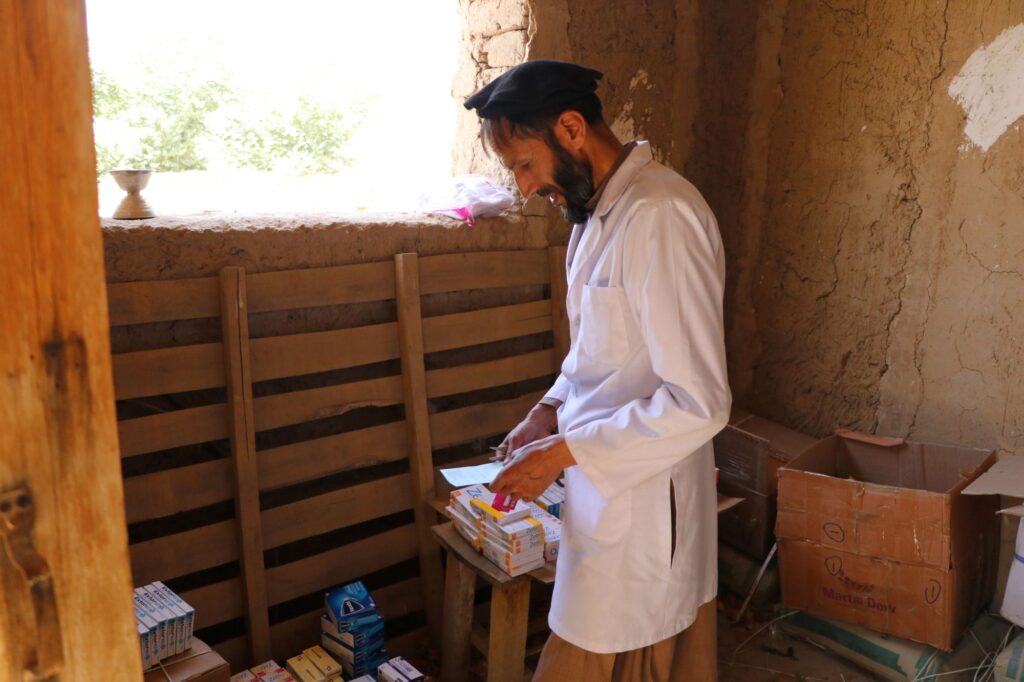 Be Team International Cure Hospital team member reviewing supplies in a mud-walled building during a free medical clinic in Afghanistan