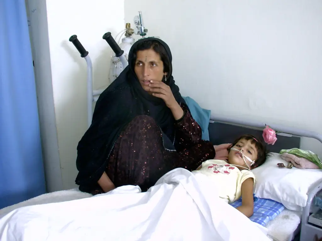 Afghan mother seated at the bedside of her young daughter recovering from a stray bullet wound at Be Team International's Cure Hospital in Kabul, Afghanistan