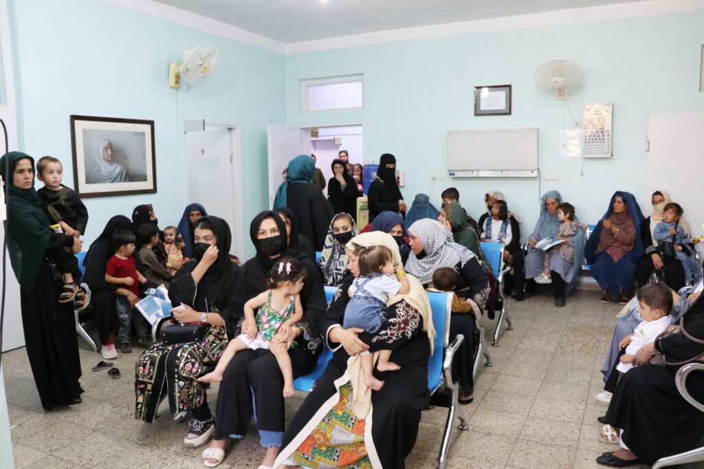Crowded waiting room of Afghan mothers in burqas and children waiting for care at Be Team International's Cure Hospital in Kabul, Afghanistan