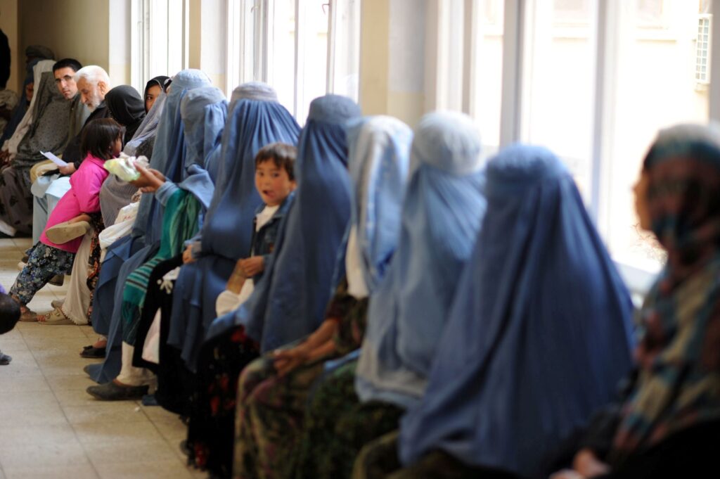 Mothers and children seated in a long line waiting for care at Be Team International's Cure Hospital in Kabul, Afghanistan