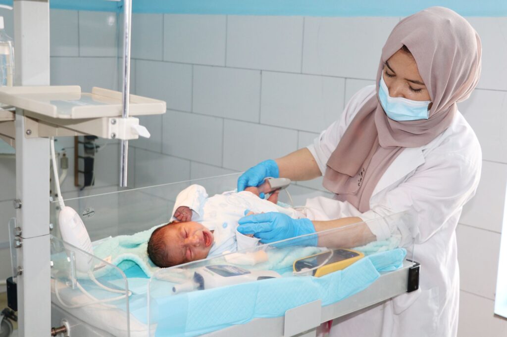 Nurse calmly caring for a crying newborn baby at Be Team International's Cure Hospital in Kabul, Afghanistan